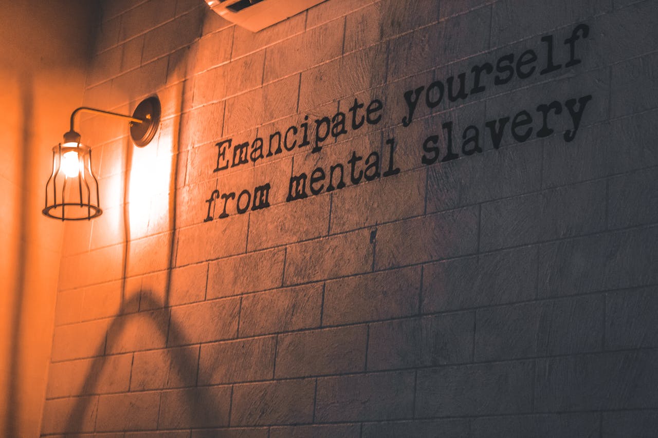 A wall lamp casts a warm glow on an inspirational quote about mental freedom.